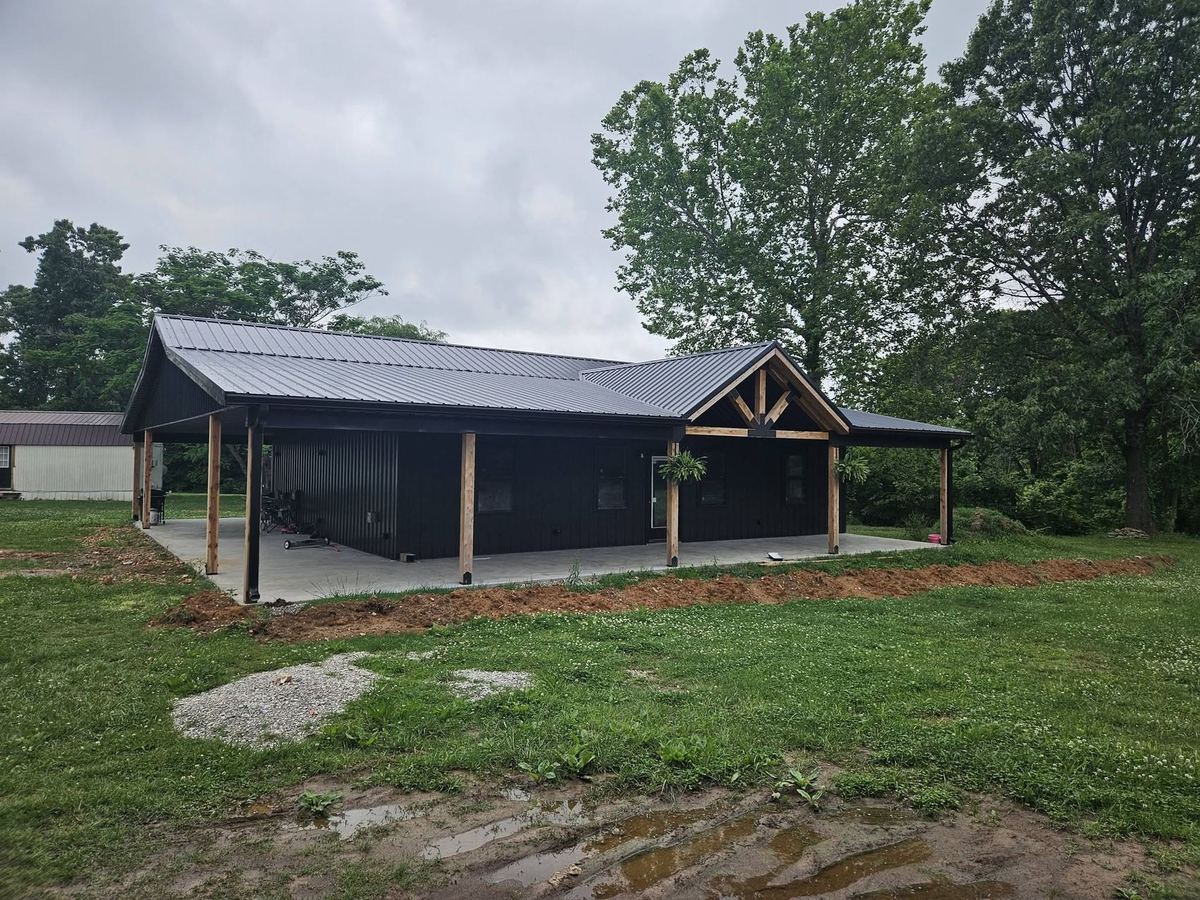 Black barndominium with a standing seam metal roof and timber porch built by SWMO Exteriors
