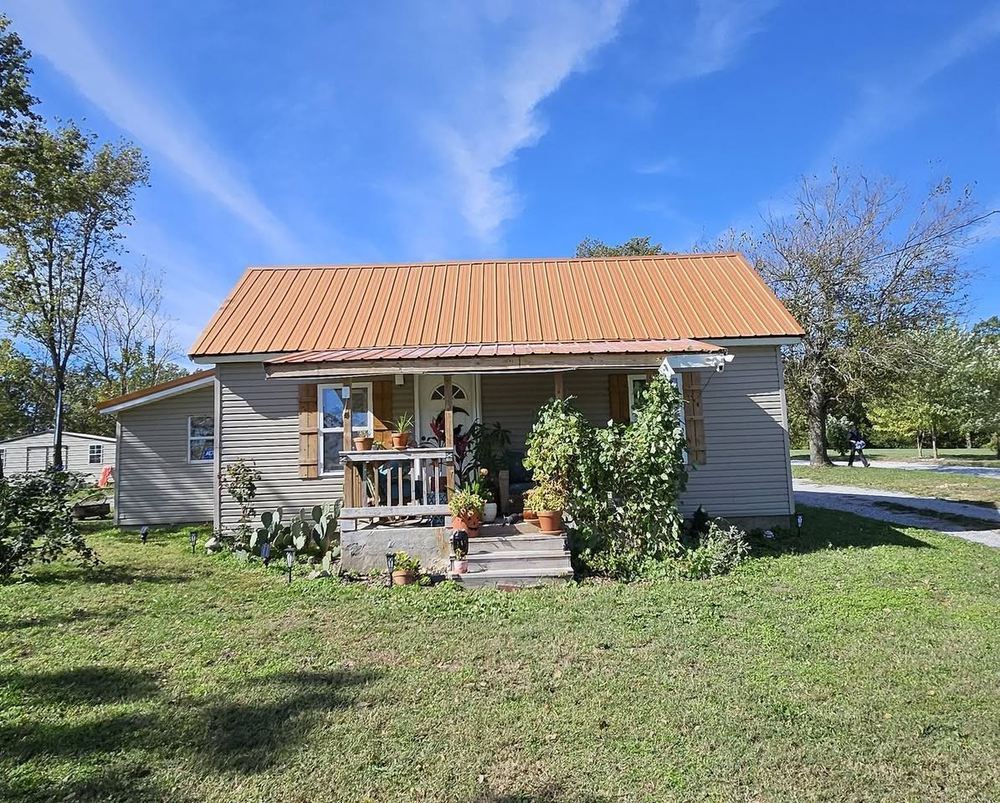 Farmhouse with a new copper-tone metal roof over lap siding
