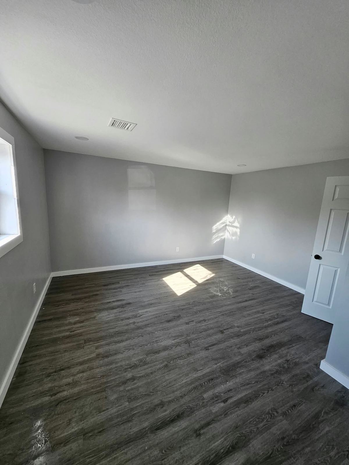Freshly finished room with dark vinyl plank flooring, gray walls and white trim