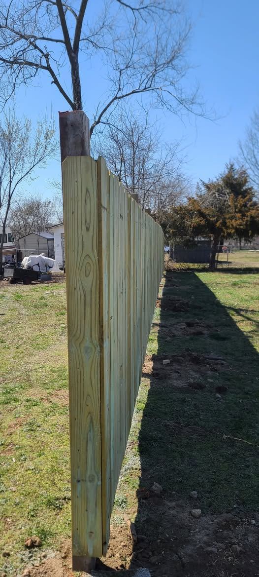Newly built wood privacy fence running along a yard line